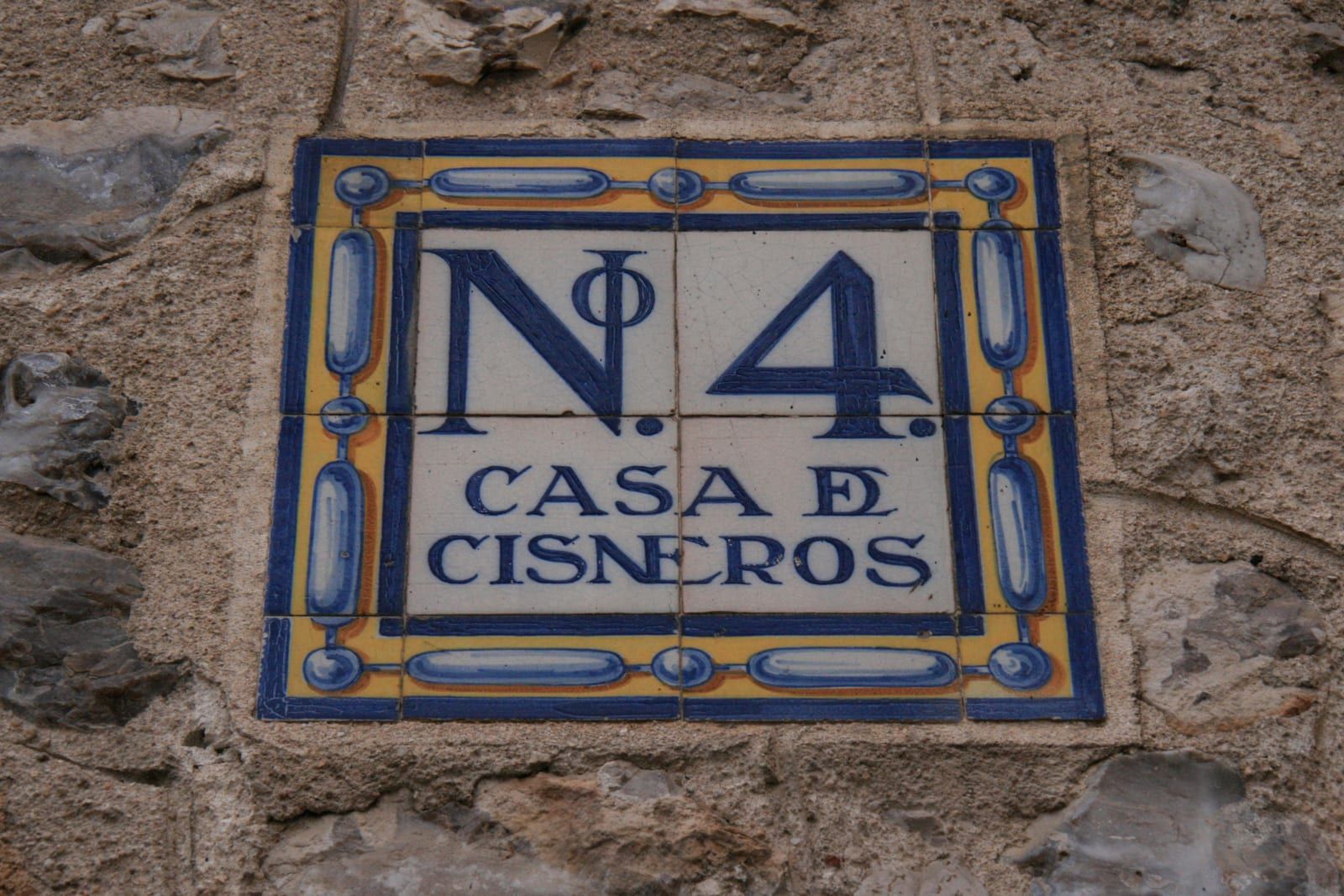 Husnummerskylt i blått och gult kakel med texten Nº 4 Casa de Cisneros